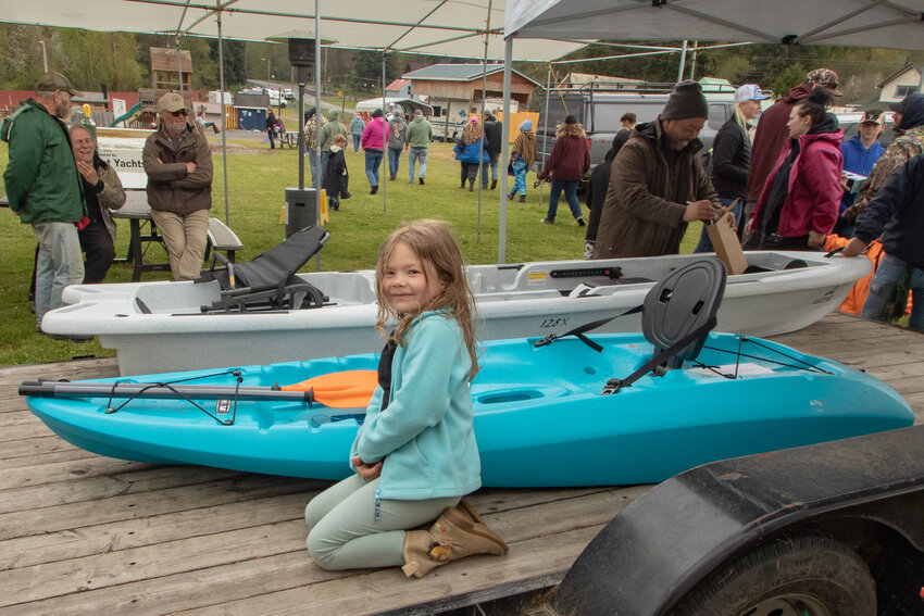 Summer Rios kneels next to a kayak she won during a raffle at the 2024 Mineral Lake Fishing Derby on Sunday, April 28, at the Mineral Lake Lions Den campground.