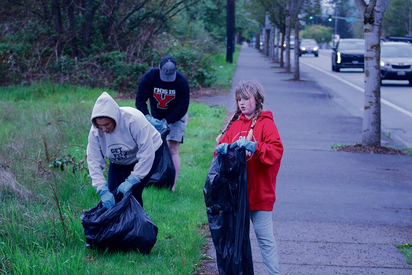 Kasey Cartledge, Jacob Panther and Kora Cartledge pick up trash across the street from Yelm High School on April 27.