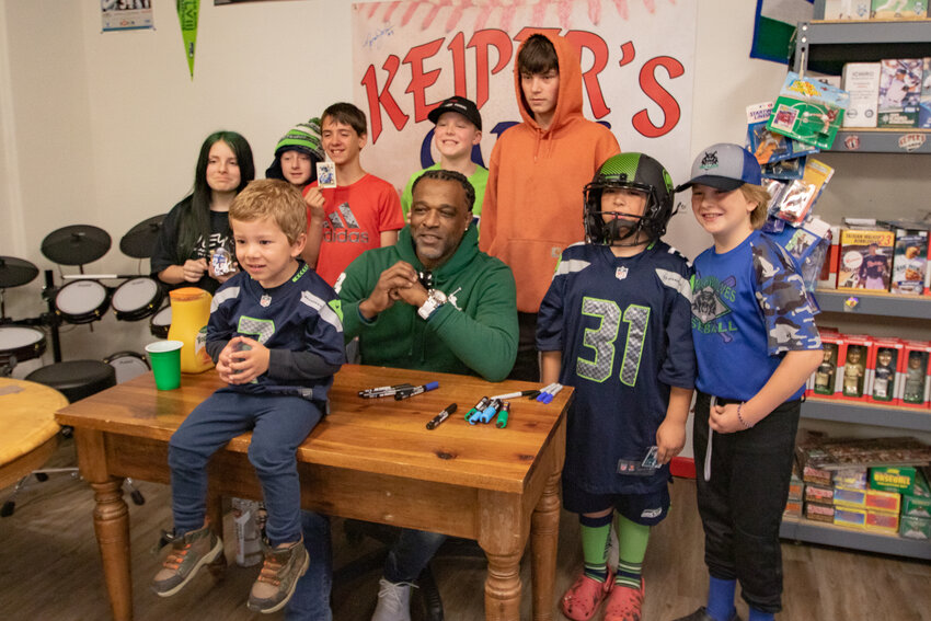 Former Seattle Seahawks running back Chris Warren, in the green sweater, poses with young fans on Sunday, May 5, during an autograph signing at the Keiper's Cards and Memorabilia Show in downtown Centralia.