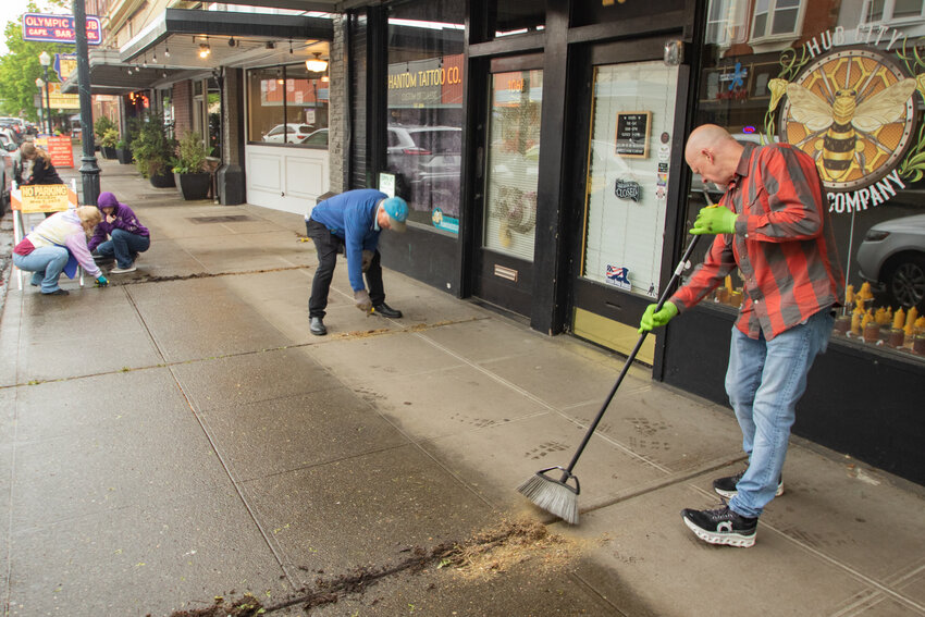 Volunteers Ron Sherrill, right, Don Haerling, center right, Catalina Cerny, center left, Sabrina Cerny, left, and Anastasia Cerny behind them work to clean the sidewalk along North Tower Avenue on Sunday, May 5, during the Centralia Downtown Association's volunteer spring cleanup event.