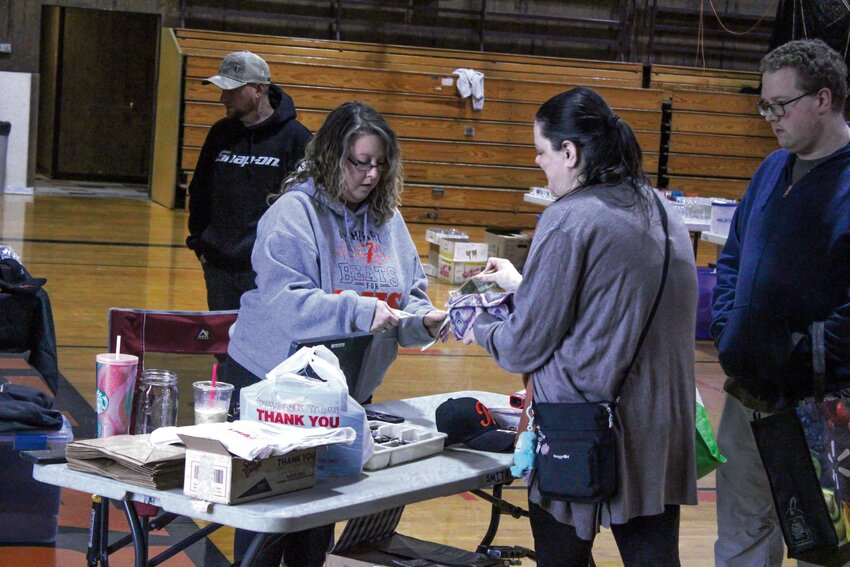 Jessica Smith (left) takes cash from customers at the Rainier High School Booster Club rummage sale on May 4.