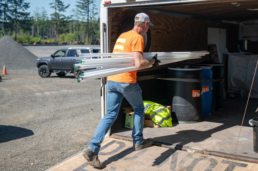 Lewis County Hazardous Waste Coordinator Kal Lersavage carries a collection of old shop lights into a trailer during a community recycle event on Saturday, May 11, at the Lewis County Public Works Department Road Shop in Napavine.
