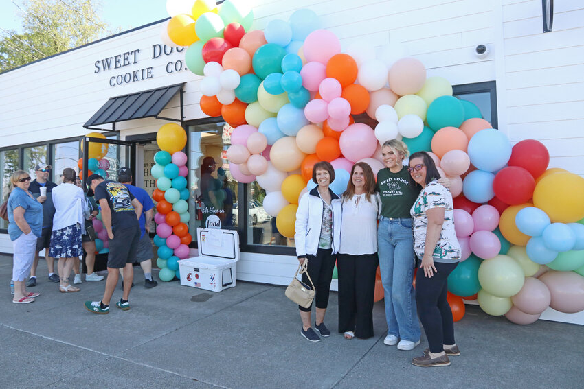 Sweet Dough Cookie Co. owner Ashlee Shirer poses for a photo with friends outside of the bakery's new Chehalis location during its grand opening on Saturday, May 11.