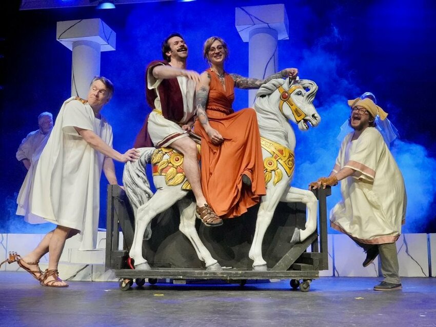 Taylor Marchant as Ron Burgundy and Zigzag Rhae as Lady Veronica Corningstone atop a steed, pushed by Tom Holt, left, and Ansel Tauber during a rehearsal.