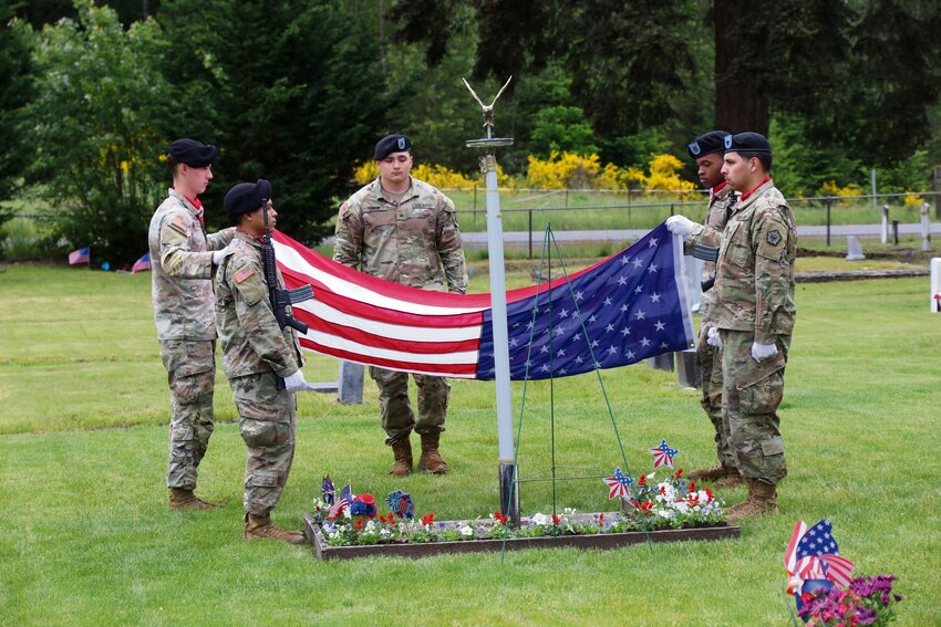 Members of the Triple Nickel raise the flag during the Memorial Day event at the Roy Historical Cemetery on May 25.