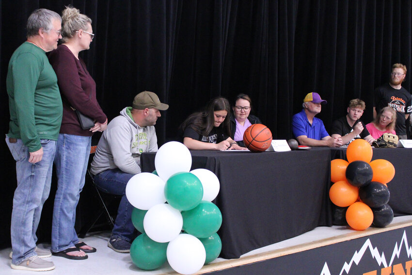Haleigh Hanson is surrounded by her family as she signs her national letter of intent with Umpqua Community College while John Kenney looks on during a signing day ceremony at Rainier High School on May 29.