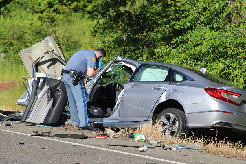 A Washington State Patrol trooper inspects a crashed Honda Accord on state Route 507 near Rainier on June 6.