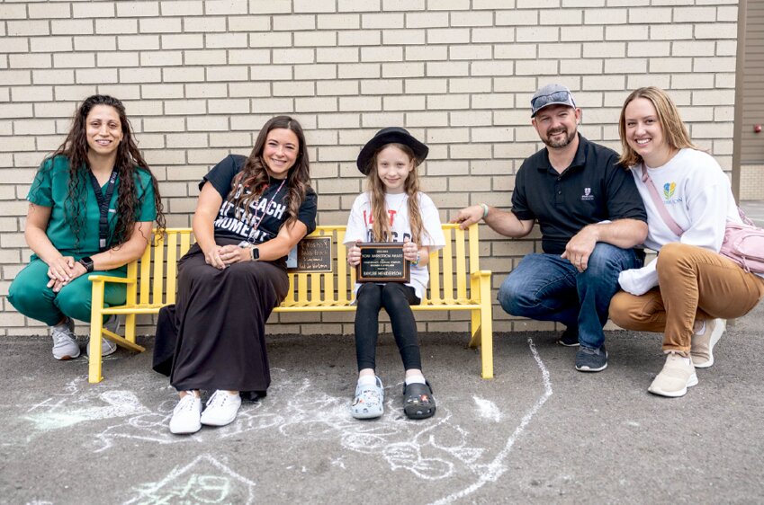The 2024 Noah Markstrom Award recipient Baylee Henderson, center, poses for a photo with her mom, Cassy Henderson, far left, teacher, Lindsay Bullock, left, and Kara and Kyle Markstrom on the Noah Markstrom Buddy Bench at Fords Prairie Elementary in Centralia on Friday, June 14.