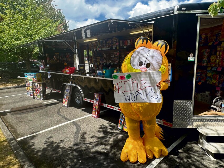 Garfield poses with a fireworks sign on June 30 outside the Yelm FFA Alumni Association's fireworks booth near the 507 Taproom on East Yelm Avenue.