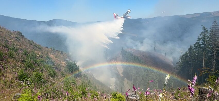 A rainbow forms as a plane dumps water on the Donkey Fire about 7 to 8 miles southwest of Pe Ell.