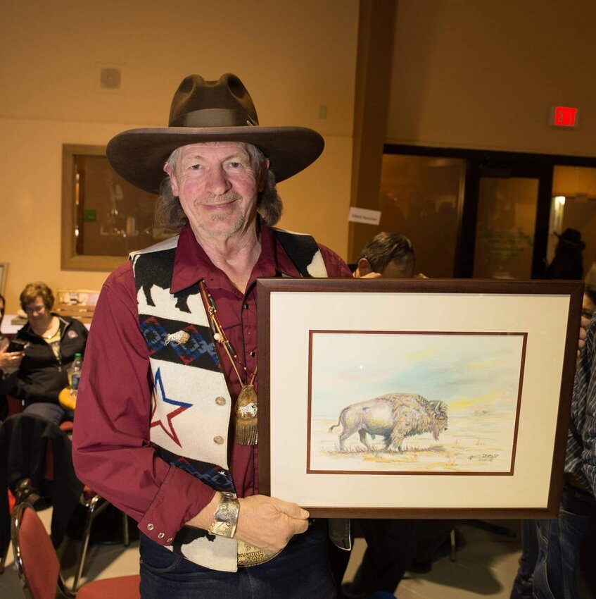 Artist Kenneth J. Hurley holds up an original painting of a buffalo in this 2018 photo.
