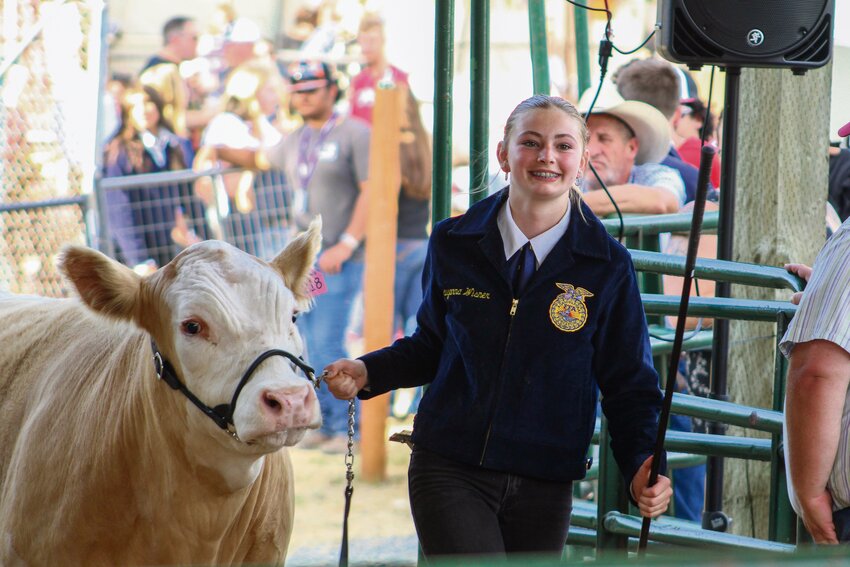 Rayanna Wisner smiles as she and her steer, Chase, enter the arena during the Thurston County Youth Livestock Auction at the Thurston County Fair on Aug. 3.