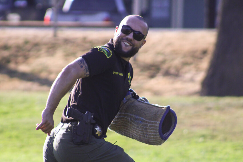 Thurston County Sheriff Derek Sanders sprints away from K9 Mac during a K9 demo at the Yelm National Night Out at Yelm City Park on Aug. 6.