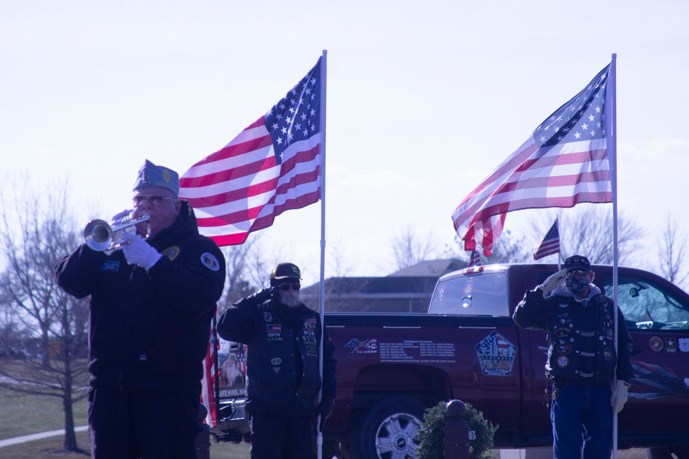 Harold Carothers plays taps in front of the display of flags closing the ceremony before the audience was dispersed to lay wreaths at Jacksonville National Cemetery.